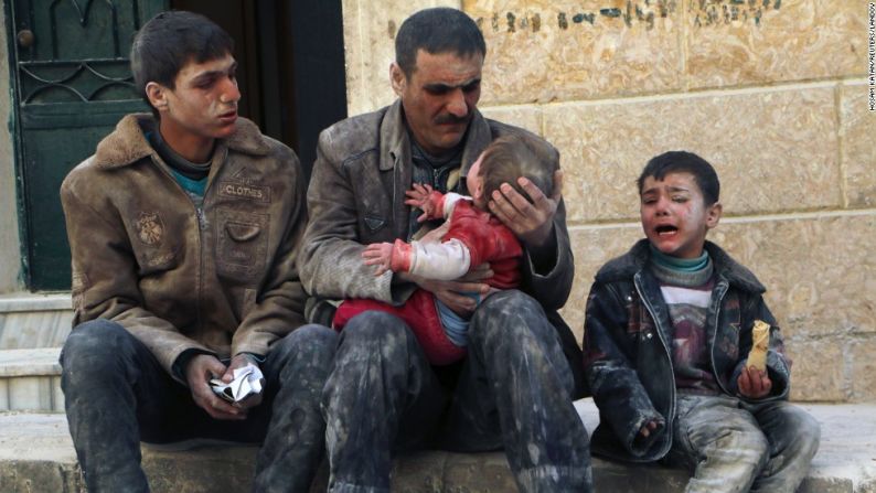 Un hombre sostiene a un bebé que sobrevivió un ataque que según los activistas fue hecho por fuerzas leales a Bashar al Assad.