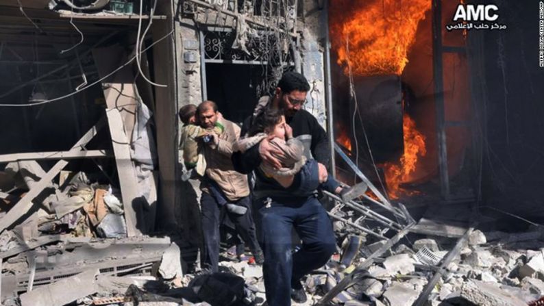 Dos rescatistas ayudan a sacar a niños de un edificio en llamas. Foto de grupo antigobierno Aleppo Media. Febrero 8, 2014.