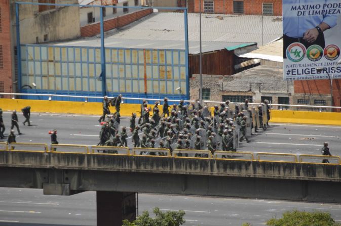 Un grupo de policías, fuertemente protegidos, se prepara para la llegada de la marcha de la oposición.