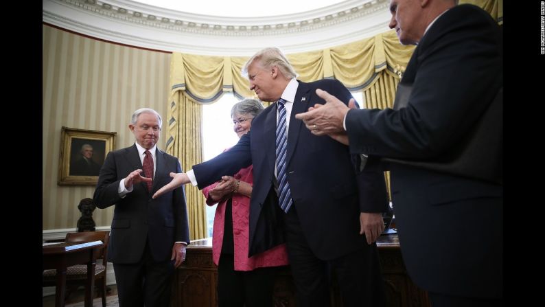 Trump le extiende su mano a Jeff Sessions, quien acaba de tomar juramento como nuevo fiscal general del país, el 9 de febrero. Sessions, uno de los asesores más cercanos del presidente y uno de sus primeros partidarios en el Senado de Estados Unidos, fue confirmado con una votación de 52 a favor y 47 en contra, que estuvo marcada por la política partidaria. Estuvo acompañado en la toma de juramento de su esposa, Mary.