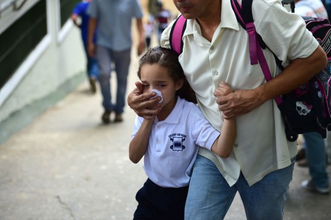 Una niña de colegio cubre su nariz y boca para evitar respirar los gases lacrimógenos que dispara la policía a los manifestantes en Venezuela.