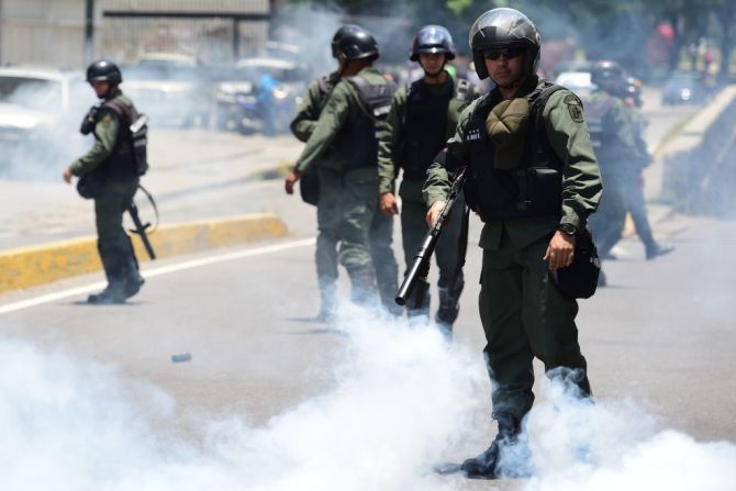 Policía antidisturbios se paran en medio de una nube de gases lacrimógenos.