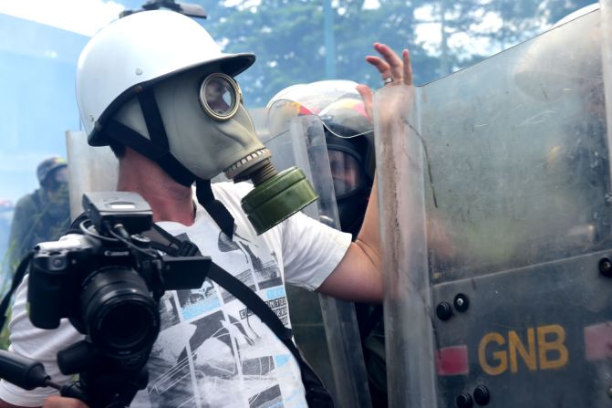 Un periodista que lleva una máscara de gas discute con la policía durante la marcha opositora.