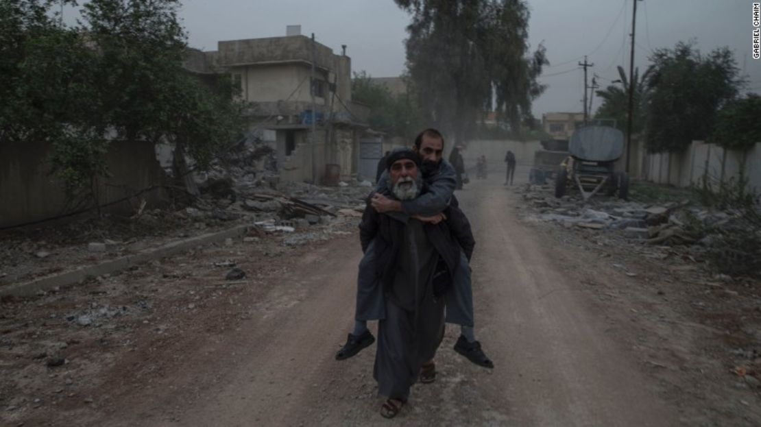 Un hombre lleva a un pariente enfermo a sus espaldas mientras huyen de su hogar en el barrio de Yarmouk, al oeste de Mosul, el 11 de abril.