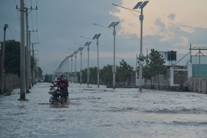 Un hombre camina mientras empuja su moto en una calle inundada en Puerto Príncipe. Este 2 de mayo del 2017 la capital de Haití se vio afectada por fuertes lluvias.