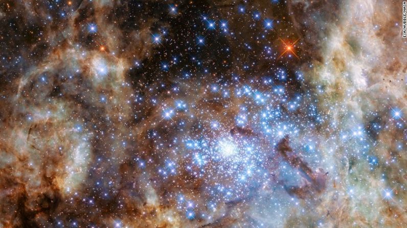 Esta imagen muestra la región central de la nebulosa de Tarántula en la nube grande de Magellanic. El joven y denso grupo de estrellas R136, que contiene cientos de enormes estrellas, es visible en la parte inferior derecha de la imagen tomada por el Telescopio Espacial Hubble.