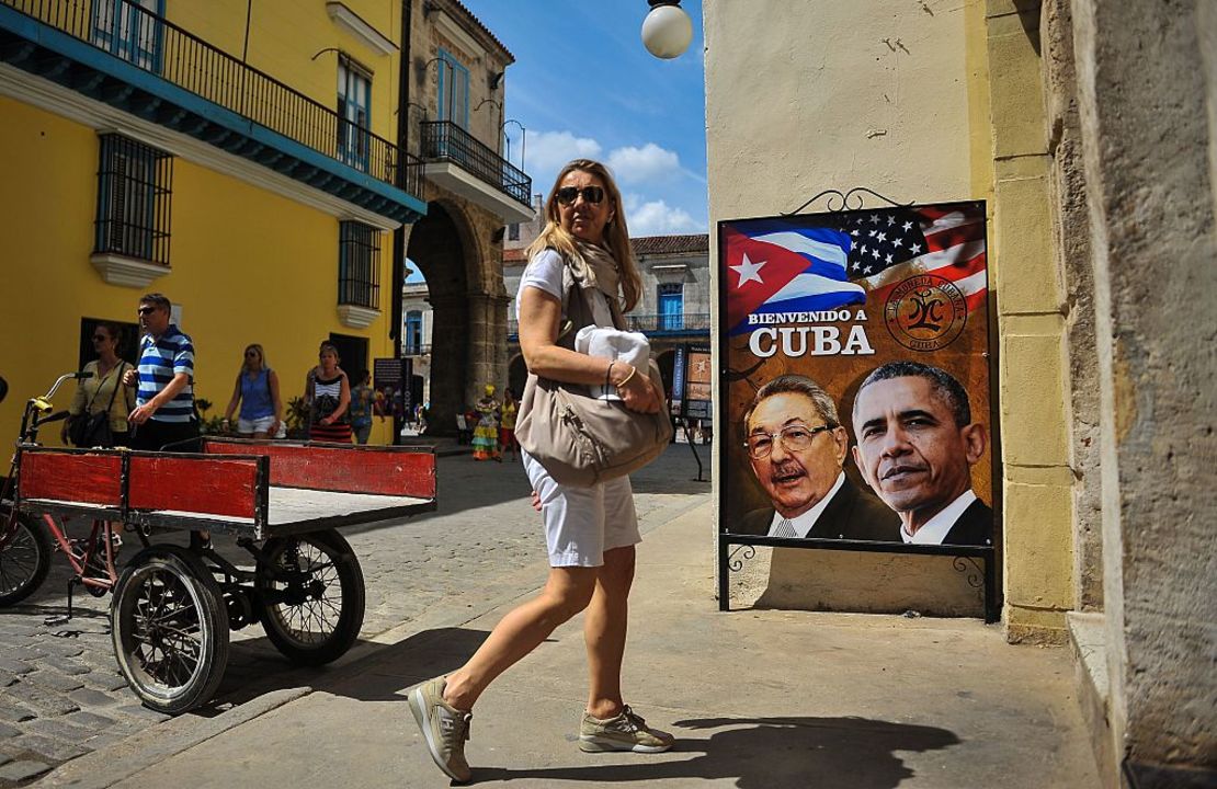 Una turista camina cerca a un cartel del presidente cubano Raúl Castro y el presidente de Estados Unidos, Barack Obama, previo a la visita de Obama a La Habana en marzo de 2016.