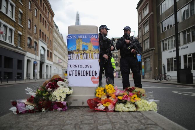 Policías permanecen cerca de ofrendas florales puestas en la escena de los ataques en Londres.