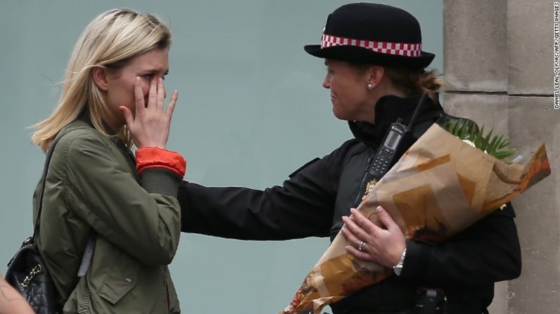 Una mujer se emociona tras pedirle a una policía que deposite flores cerca del Puente de Londres como un homenaje a las víctimas del ataque.