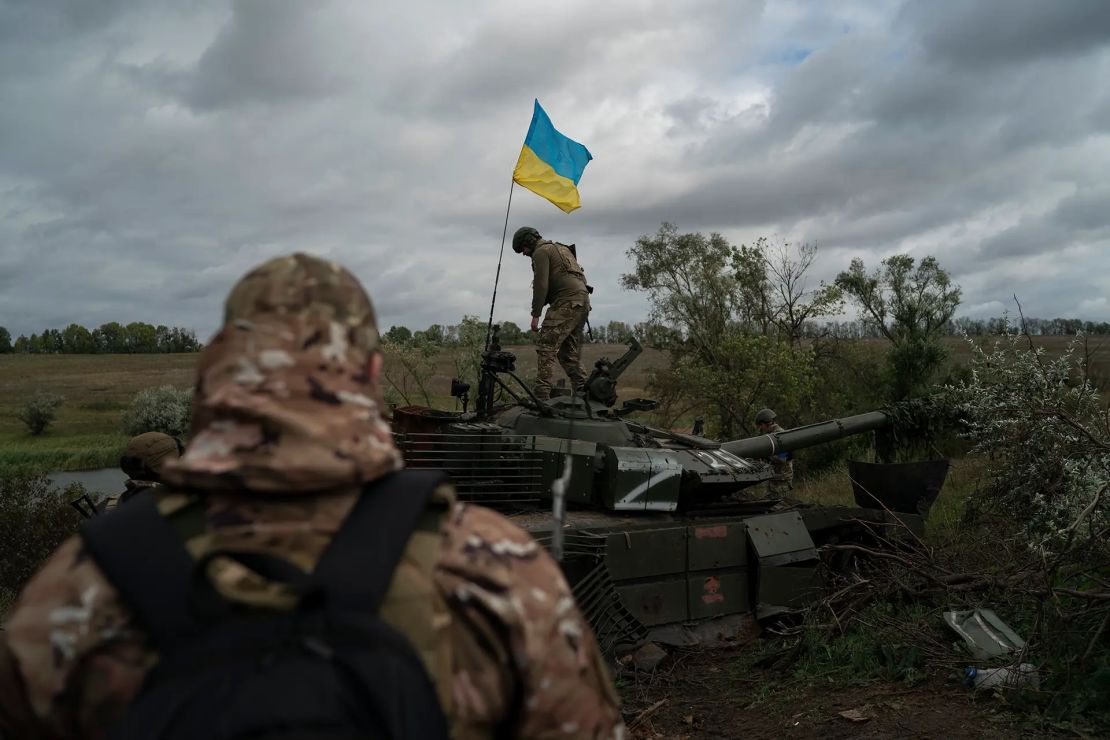 Un miembro de la guardia nacional ucraniana junto a una bandera ucraniana encima de un tanque ruso destruido en la región de Járkiv.