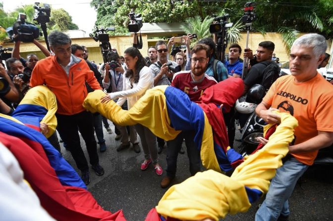 Simpatizantes de López desenrollan banderas venezolanas afuera de su casa.