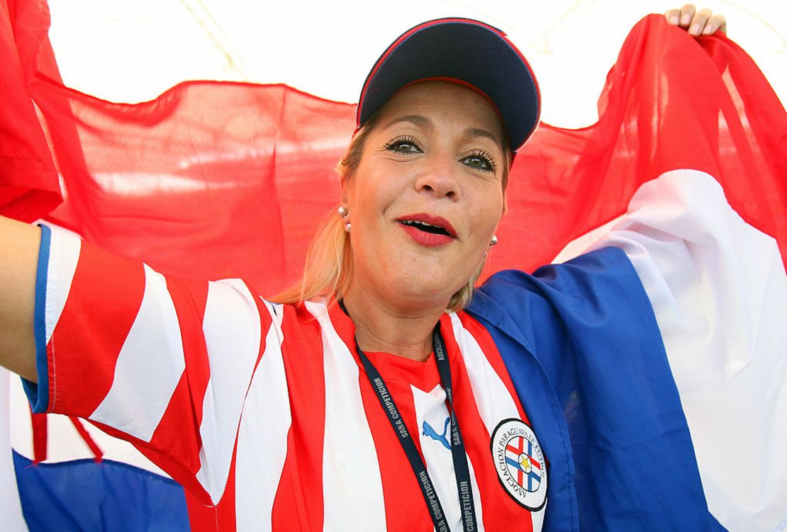 CNNE 430008 - a paraguay fan cheers while holding the