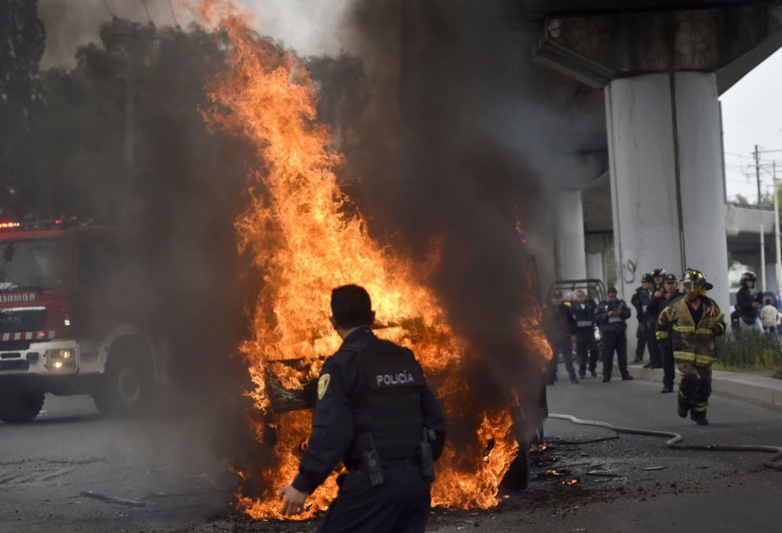 Bomberos y policías de Ciudad de México apagan los incendios de vehículos en el sector de Tlahuac en Ciudad de México, en medio de un operativo policial contra delincuencia organizada en la capital mexicana el 20 de julio de 2017.