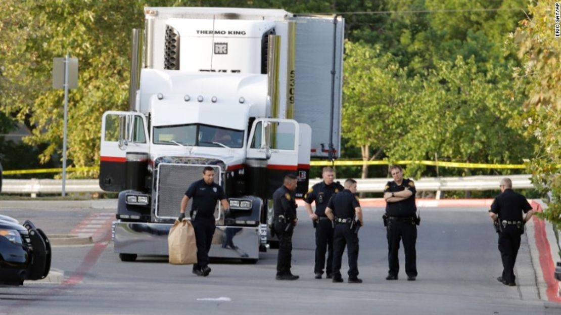 Policías investigan en la escena donde fue hallado un tráiler con 39 personas en su interior, varias de ellas muertas.