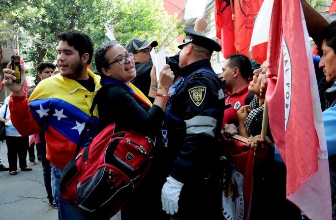 Un agente de policía separa a los miembros del Frente Popular Francisco Villa (d), que apoyan al presidente venezolano, Nicolás Maduro, y miembros de la comunidad venezolana en México, que se manifiestan en contra de las elecciones para la Asamblea Constituyente en la embajada de Venezuela en Ciudad de México este 30 de julio de 2017.