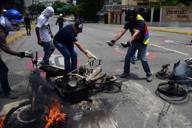 Activistas opositores arrastran motocicletas policiales ardientes en llamas durante una manifestación en contra de la Asamblea Nacional Constituyente en Caracas este 30 de julio del 2017.