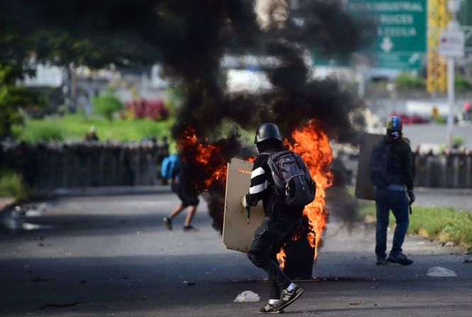 Un manifestante opositor choca contra fuerzas policiales durante una manifestación en contra de la Asamblea Nacional Constituyente en Caracas este 30 de julio del 2017. En algunas calles de la capital de Venezuela se observan manifestantes y policías enfrentados entre bombas improvisadas, gas lacrimógeno y perdigones.