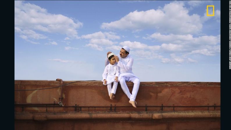 "Puente de generaciones". La primera mención honorífica en la categoría de Personas es para Jobit George. He aquí cómo George describe su fotografía: "Una hermosa foto de un padre y su hijo sentado con su traje tradicional blanco con el marco de un hermoso cielo azul en el día de Eid al-Fitr, en una mezquita, en Nueva Delhi (India). Dos generaciones se juntan de una manera muy simple y amable".