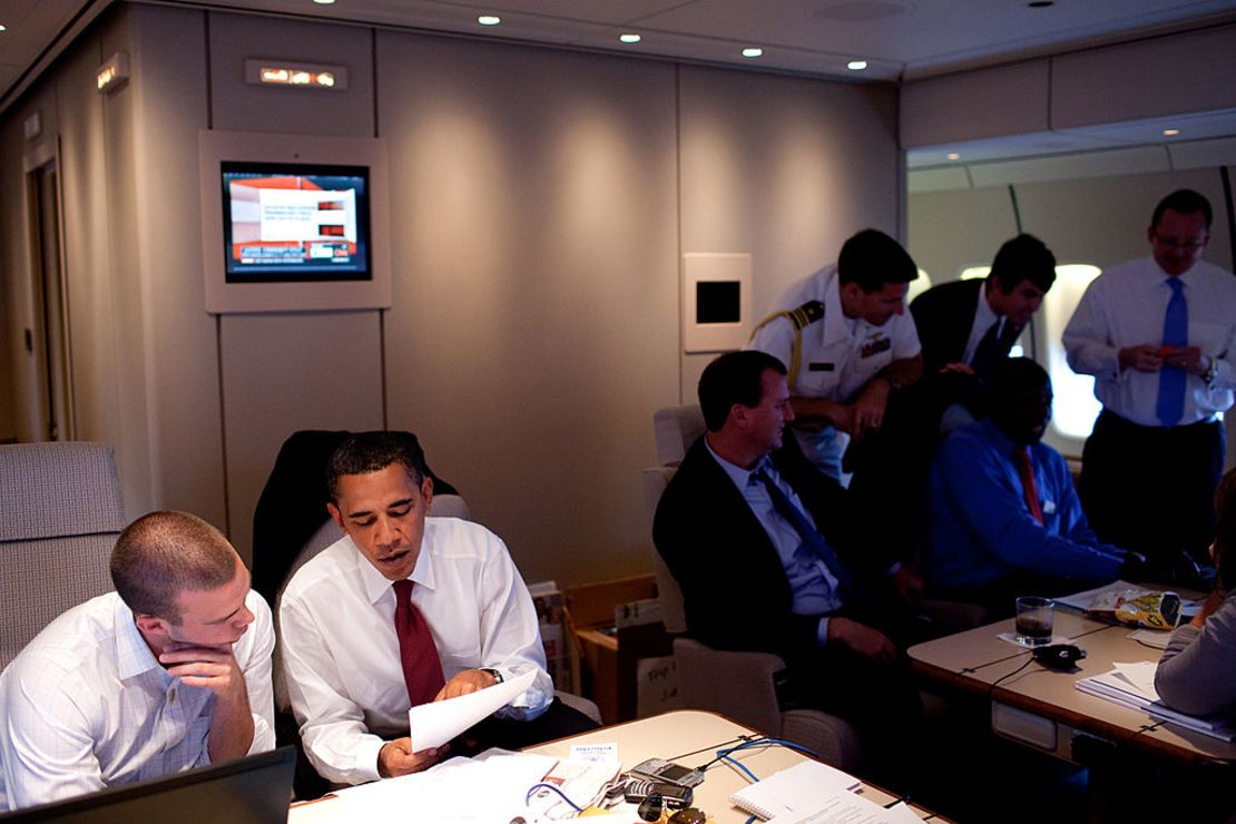 Barack Obama en el 2009 trabajando en el avión presidencial. Detrás de él, una TV encendida en CNN.