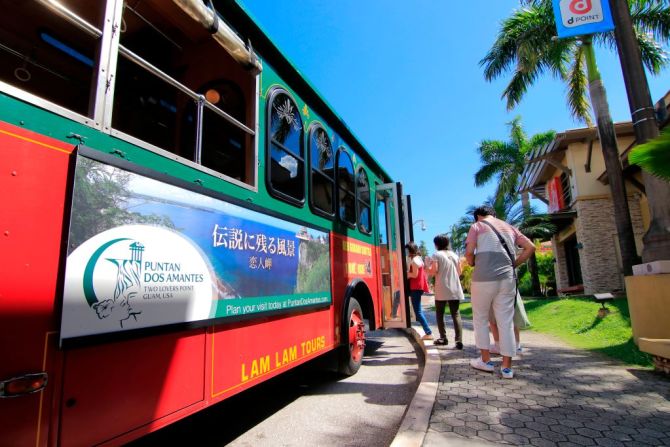 Turistas suben a un autobús en una calle en Tamuning.