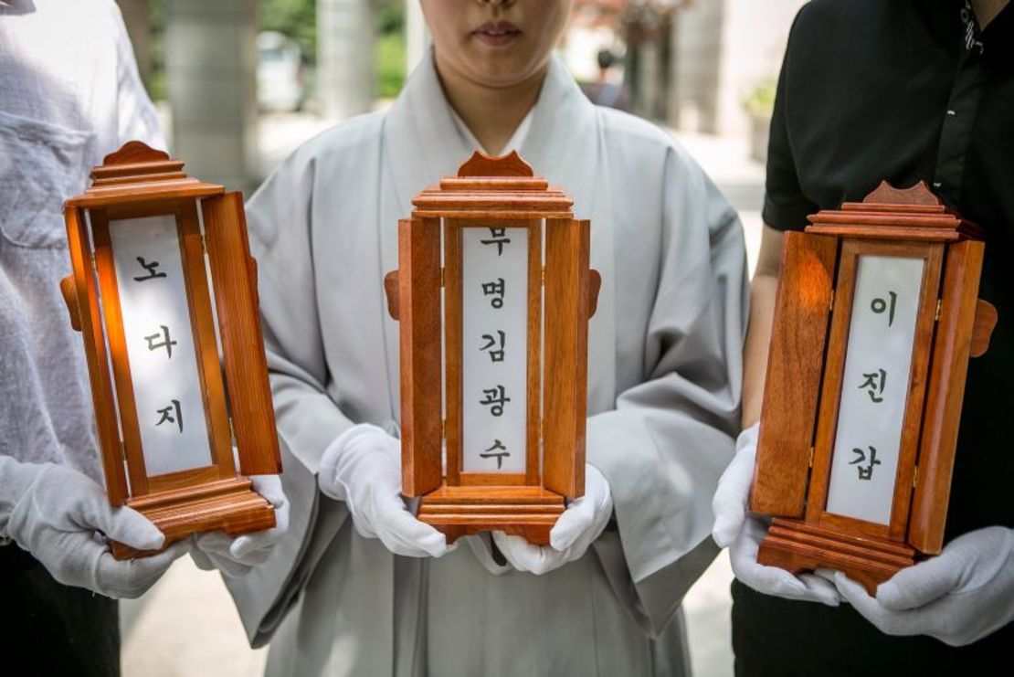 Una monja budista y el personal de Good Nanum sostienen las placas con los nombres de tres personas fallecidas antes de su cremación el 16 de junio de 2016 en Goyang, Corea del Sur.