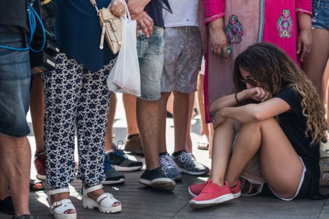 Una mujer llora sentada en Las Ramblas junto a los múltiples homenajes a las víctimas.