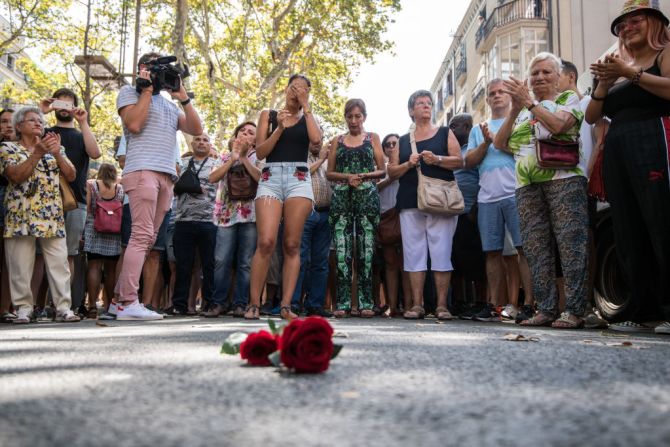 Un grupo de personas se reúne junto a unas rosas dejadas en el suelo de Las Ramblas.