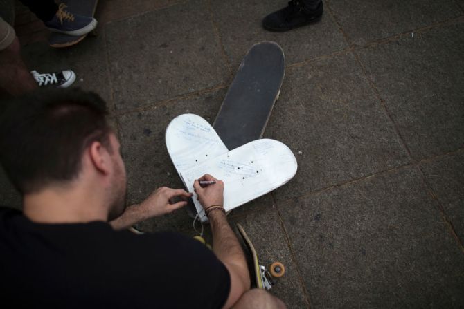 Un patinador escribe un mensaje en un corazón sobre su patineta para dejarlo en uno de los homenajes en Las Ramblas.