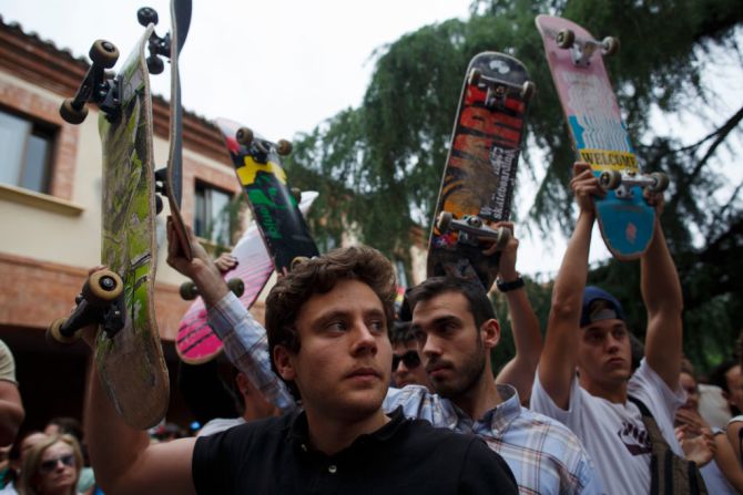 Los patinadores elevan sus patinetas mientras cantan por las víctimas de Barcelona.