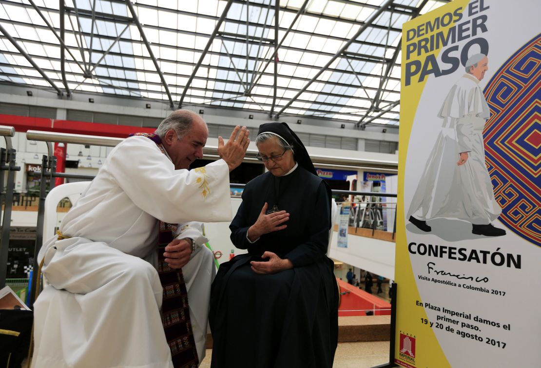 Un padre oye la confesión de una penitente durante la jornada de la Confesatón en un centro comercial de Bogotá.