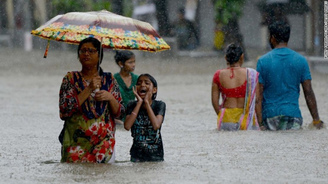 Indios caminan por una calle inundada este martes durante las fuertes lluvias en Mumbai.