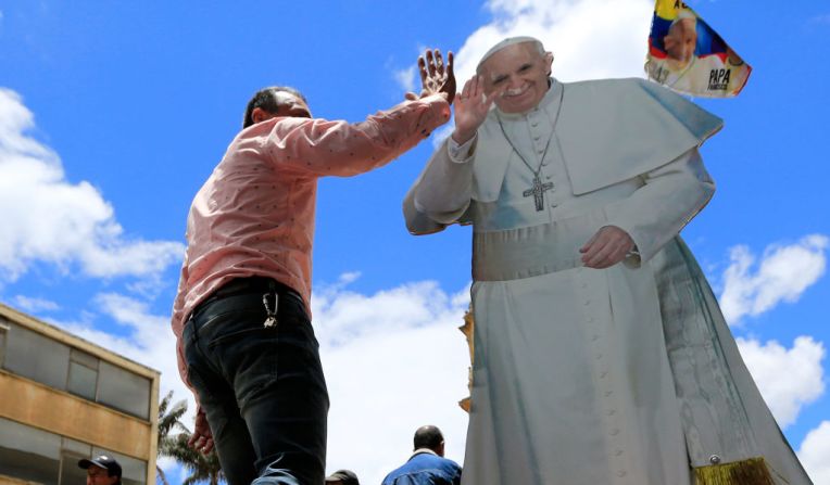 Un hombre choca su mano con la del ‘papa’ en una calle de Bogotá. Es una imagen de tamaño real cerca del palacio del arzobispo en Bogotá.