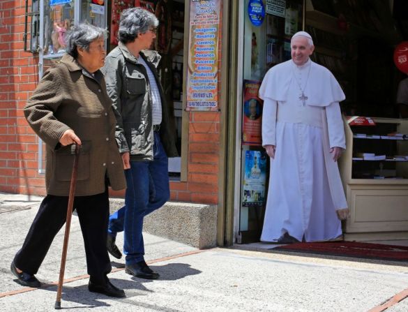 Peatones pasan cerca de una imagen de tamaño real del papa en una calle de Bogotá. Antes de su llegada al país el pontífice dijo que se siente honrado de visitar Colombia. El lema de su viaje es "demos el primer paso".