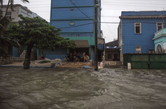 Habitantes de La Habana se sientan en el pavimento en una calle inundada durante el paso del huracán Irma.