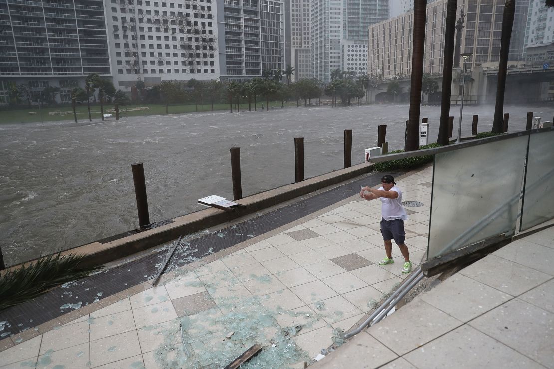 Una persona trata de tomar fotos de la inundación de las aguas del río Miami causada por el huracán Irma.