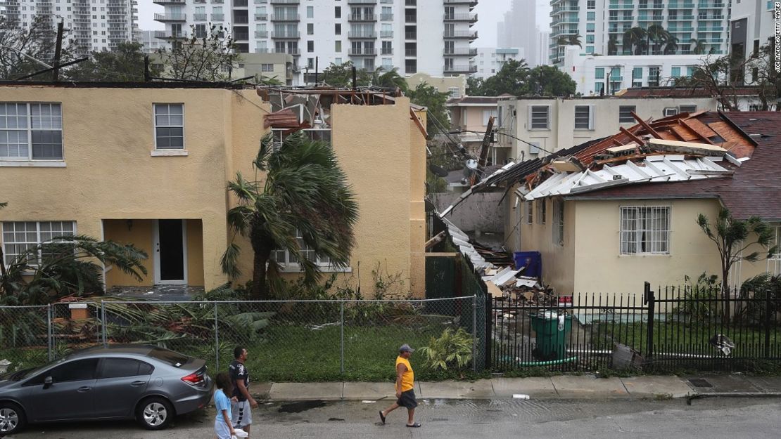 Las personas caminan frente a un edificio cuyo techo fue desprendido por los fuertes vientos de Irma en Miami.