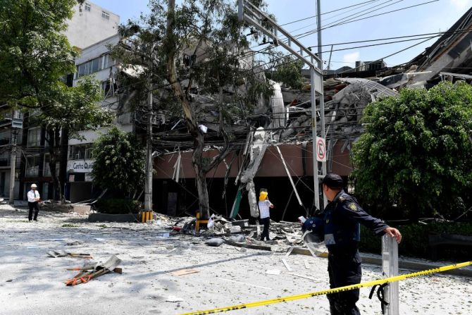 Un policía y otras personas observan el colapso de un edificio en Ciudad de México tras el terremoto de 7,1.