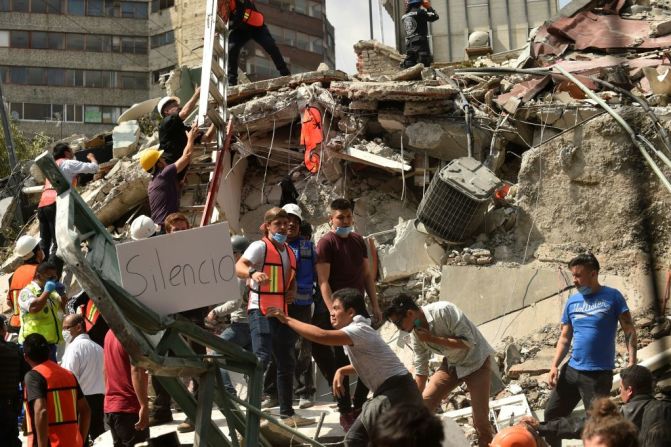 Los rescatistas exhiben un cartel de "Silencio", durante la búsqueda que hacen en medio de los escombros, para poder encontrar a posibles sobrevivientes que se encuentren atrapados.