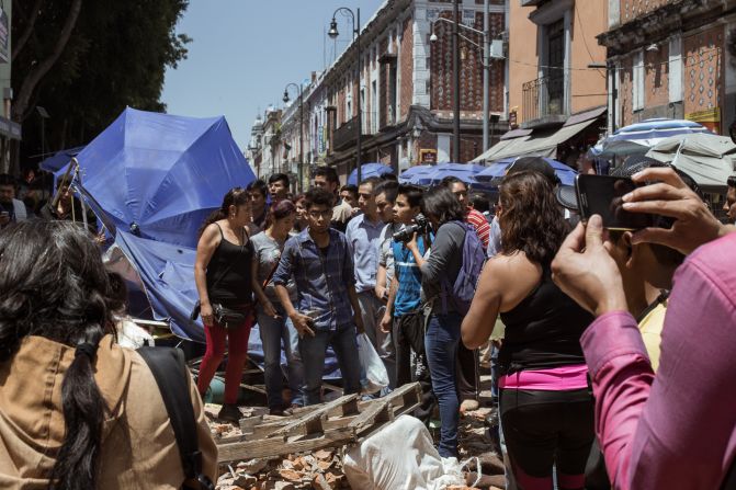 Un grupo de personas se aglomera alrededor de parte de los escombros que produjo en Puebla el terremoto de 7,1 que vivió México.