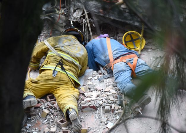 Un bombero y un rescatista buscan alguna señal de vida entre grietas y escombros causados por el devastador terremoto.