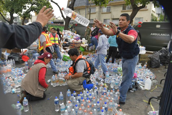 Voluntarios distribuyen agua y otras bebidas donadas en un punto de distribución, mientras la búsqueda de supervivientes continúa en la Ciudad de México.