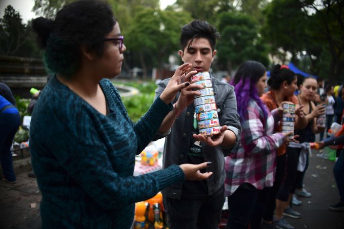 Personas que se visten de héroes anónimos para asistir a los afectados con alimentos y otros suministros donados en un punto de distribución.