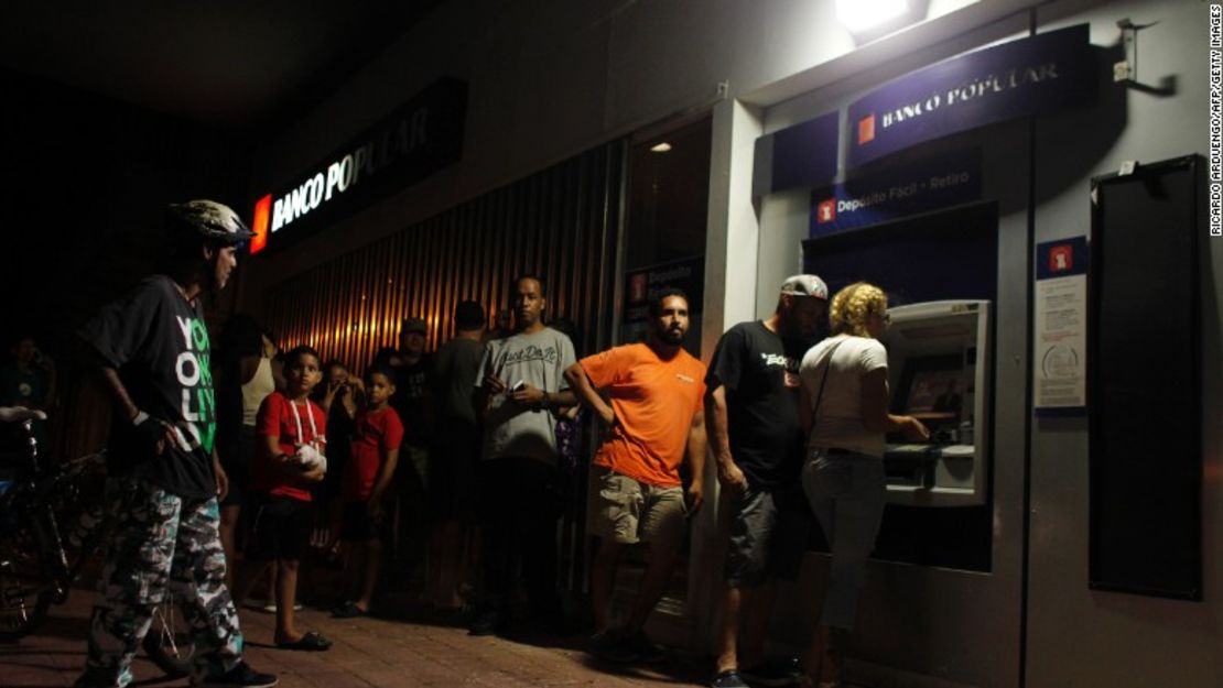 Puertorriqueños hacen fila en un cajero automático para retirar dinero en San Juan.