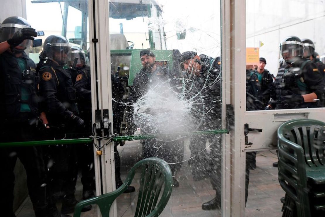 Miembros de la Guardia Civil rompen la puerta de cristal del centro de votación donde votaría el presidente catalán.