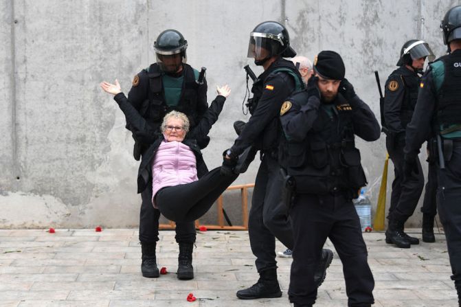 Una mujer mayor es retirada por la fuerza por agentes de la policía en un centro de votación en Sant Julia de Ramis.