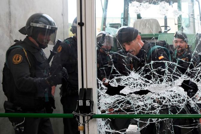 Agentes de la Guardia Civil rompen la puerta de cristal del centro de votación de Sant Julia de Ramis, donde votaría el presidente catalán, Carles Puigdemont.