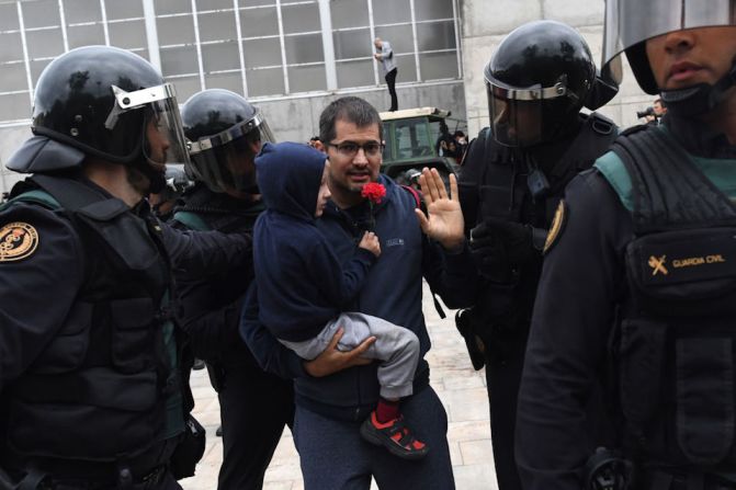 La policía rodea a un hombre y un niño afuera del centro de votación donde votaría el presidente del gobierno catalán, Carles Puigdemont, en Sant Julia de Ramis.