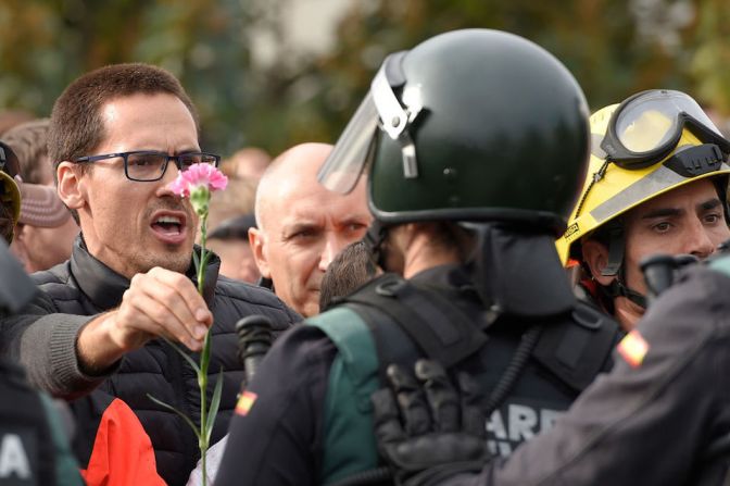 Un hombre sostiene un clavel frente a un agente de la Guardia Civil española afuera de un centro de votación en Sant Julia de Ramis.