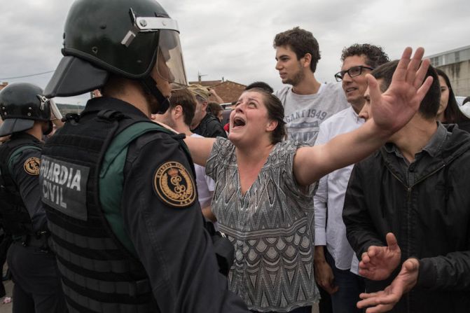 Personas levantan sus brazos mientras la policía impide que voten en Sant Julia de Ramis.