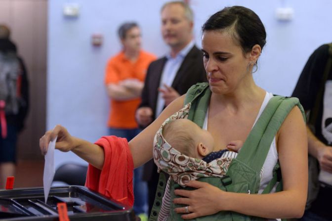 Una mujer llevando a su bebé vota en Barcelona.